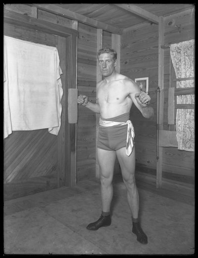 Boxeador inglés William Thomas Wells (Bombardier Billy Wells), posando en ropa de entrenamiento con poleas de peso, c.1911 de William Davis Hassler