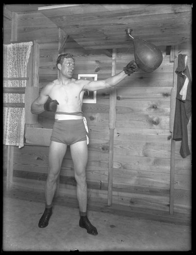 Boxeador inglés William Thomas Wells (Bombardier Billy Wells), posando en ropa de entrenamiento con una bolsa de velocidad, c.1911 de William Davis Hassler