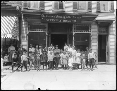 Retrato de grupo de niños frente a la sucursal Steinway de la Biblioteca Pública del Distrito de Queens, c.1910 de William Davis Hassler