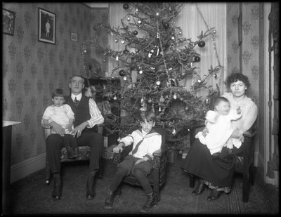 Retrato grupal informal de una familia no identificada en su apartamento sentados frente a un árbol de Navidad, Nueva York, c.1915-16 de William Davis Hassler