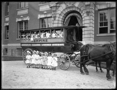 Niñas pequeñas posan en y frente a un carro tirado por caballos, frente a un edificio no identificado, probablemente el Asilo de Huérfanos Católico Romano, Kingsbridge, Bronx, c.1910 de William Davis Hassler