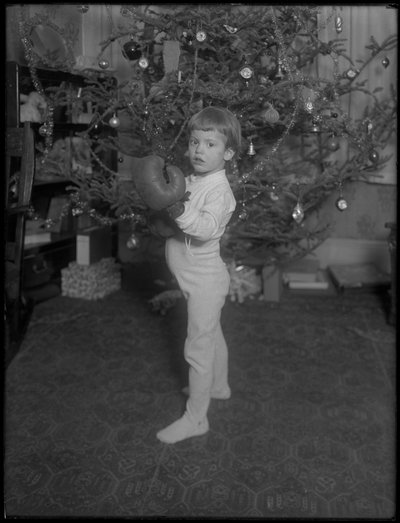Niño no identificado frente a un árbol de Navidad con guantes de boxeo, 1915-16 de William Davis Hassler
