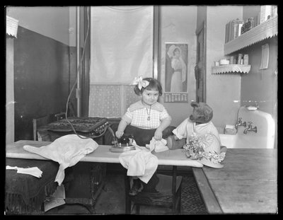 Niña no identificada demostrando el uso de una plancha eléctrica, c.1913-14 de William Davis Hassler