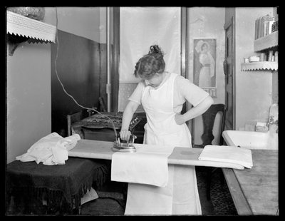 Mujer no identificada demostrando el uso de una plancha eléctrica c.1913-14 de William Davis Hassler