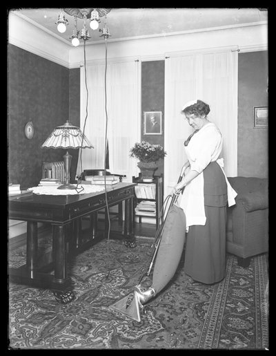 Mujer no identificada demostrando el uso de la aspiradora Apex, c.1913-14 de William Davis Hassler