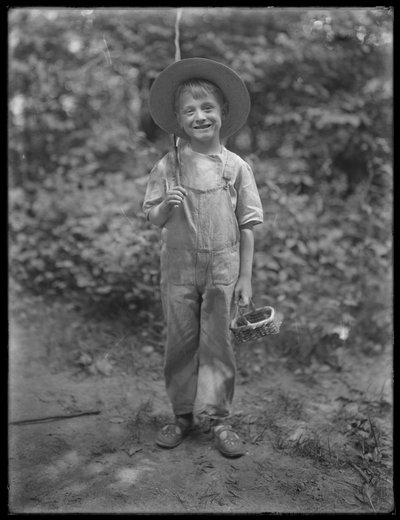 William Gray Hassler con sombrero de paja y overol, llevando una caña de pescar y una cesta en el bosque, 20 de agosto de 1911 de William Davis Hassler