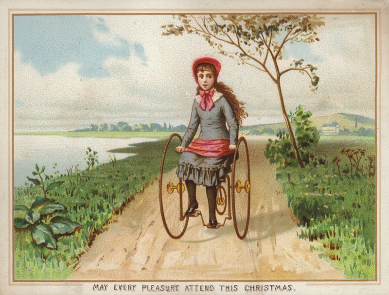 Niña montando un triciclo en el campo de American School