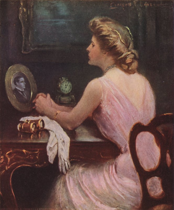 Mujer sentada en su tocador mirando una fotografía de un hombre, posiblemente su esposo o amante de Clarence F. Underwood