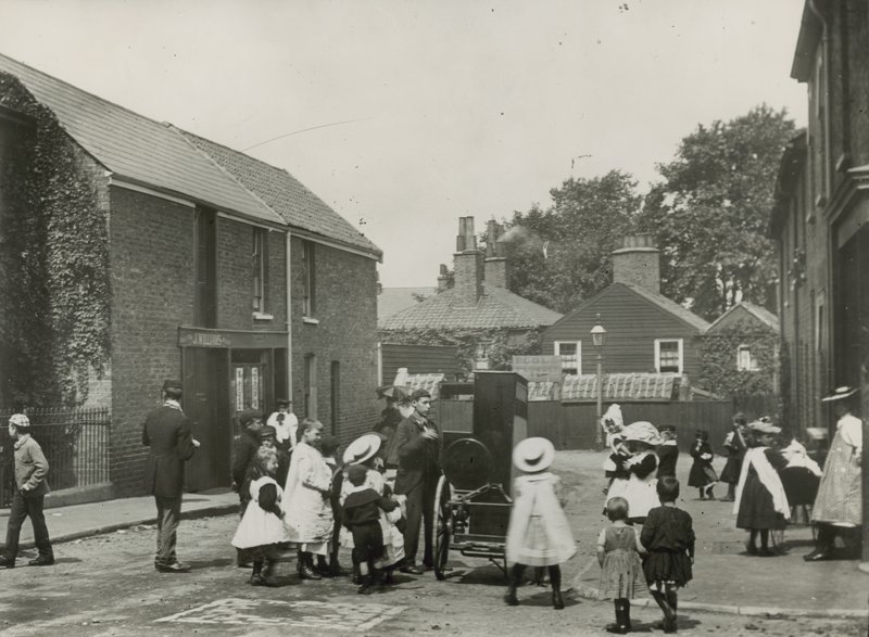 Multitud de niños se reúne alrededor de un órgano de calle de English Photographer