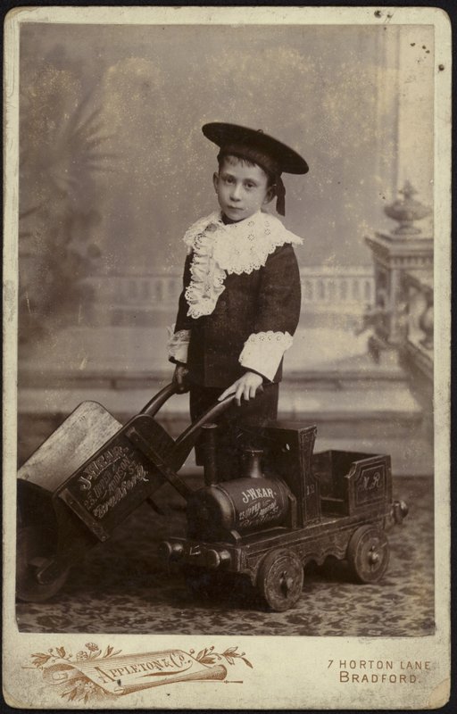 Retrato de un niño pequeño posando con un carrito de mano de English School