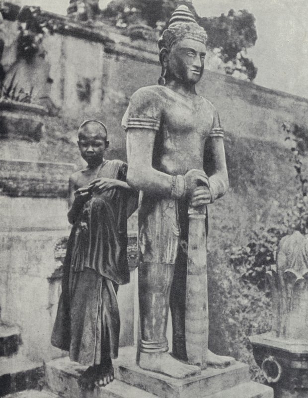 Joven monje budista novicio junto a una estatua de Buda, Indochina francesa de Ewing Galloway