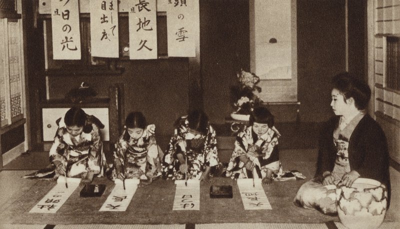 Escolares japonesas escribiendo con pinceles en una clase de jardín de infantes de Photographer Japanese