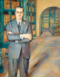 Retrato del notario vestido con traje, corbata y gafas, en su biblioteca con estanterías llenas de libros.