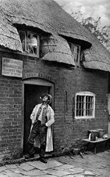 Un hombre fumando una pipa fuera de una tienda, Worcestershire, c1922