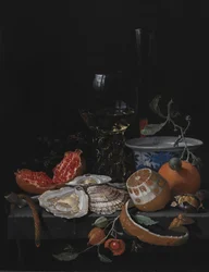 Ostras, fruta y una copa de vino en una mesa de piedra