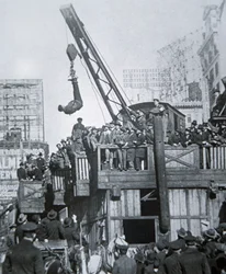 Houdini escapando de una camisa de fuerza mientras está suspendido de una grúa en la ciudad de Nueva York