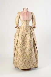 Vestido de seda marrón claro tejido con un diseño de flores malva, azules y amarillas y hojas verdes, panel y puños de seda acanalada rosa claro
