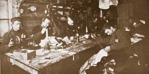 En la cabaña, en pleno invierno, los hombres se dedican a coser pieles para la ropa que se utilizará en la primavera en trineo, pub. Londres 1907 (foto en blanco y negro)