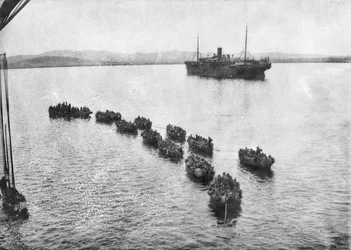 Tropas australianas siendo remolcadas a la orilla en lanchones para desembarcar en Anzac Cove, Gallipoli. En el fondo está el barco de transporte, 1915