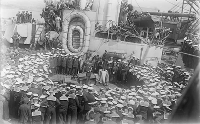 Marineros rodean al Primer Ministro australiano El Honorable William Morris (Billy) Hughes mientras les habla en la cubierta del HMAS Australia en el astillero en Devon, Inglaterra, 21 de mayo de 1916