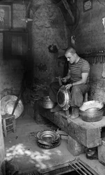 Metalúrgico italiano martilleando sobre una chapa encofrada para fabricar una vasija u olla elevada, Italia