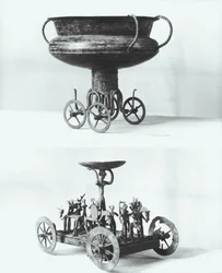 Dos carros votivos para recolectar agua de lluvia: Arriba - copa sostenida sobre cuatro ruedas del túmulo de Peccatel, Mecklemburgo, Alemania. Abajo - divinidad femenina de pie bajo un plato rodeada de guerreros