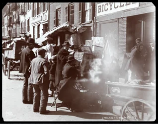 Vista de vendedores ambulantes, incluyendo uno que muestra vistas fotográficas de lugares exóticos en una caja de vistas, en Bayard Street, Nueva York, 1898