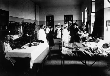 Salón decorado en un hospital con heridos de guerra, médicos, enfermeras de la Cruz Roja y visitantes