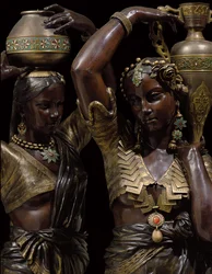 Detalle de dos antorchas de bronce en forma de mujeres indias llevando jarrones