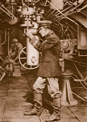 Oficial de submarino británico examinando el periscopio con la esperanza de encontrar un objetivo enemigo.