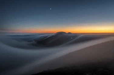 Las montañas al atardecer sobre las nubes
