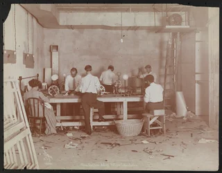 Laboratorios de cine en Carlton Motion Picture Co. con cinco hombres y una mujer trabajando con películas, empalmando, etc., Nueva York