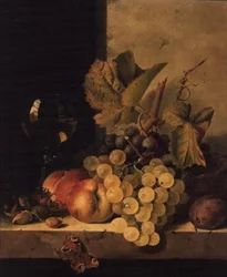 Uvas, duraznos y una copa de vino en un borde