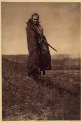 Un Grizzly-Bear Brave, Piegan. Al menos dos de las Sociedades de Guerra Piegan (los Valientes y Todos los Perros Valientes) incluían a dos hombres conocidos como el Valiente Oso-Grizzly. Durante las fiestas, era su responsabilidad proporcionar carne a sus 