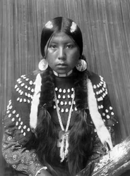 Mujer india kalispel, rayas blancas pintadas en el pelo, pendientes de disco de concha, con vestido de manta decorado con dientes de alce, c. 1910, foto Edward S. Curtis