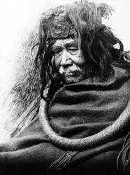 The Hamatsa, Nakoaktok c. 1910 Retrato de medio cuerpo de un hombre de Nakoaktok, mirando hacia la izquierda, con un lazo ceremonial de raíz de cedro.