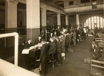 Inmigrantes siendo registrados en el Salón Principal, Estación de Inmigración de EE. UU., 1902-10