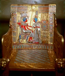 Antigüedades egipcias: un trono de madera dorada y pintada de Tutankamón que forma parte del tesoro del faraón. Representación de la reina Ankhesenpaaton masajeando con aceite el hombro de su hermano y esposo Tutankamón bajo el sol