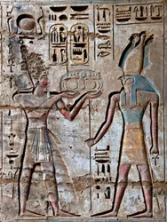 Antigüedad egipcia: primer patio, detalle de relieves pintados que representan al faraón llevando ofrendas a la divinidad Horus. Templo funerario de Ramsés III (1187-1156 a.C.). Luxor, Medinet Habou, Egipto