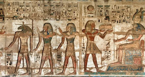 Antigüedad egipcia: primer patio, detalle de relieves pintados que representan al faraón llevando ofrendas a las divinidades Horus y Jnum. Templo Funerario de Ramsés III (1187-1156 a.C.). Luxor, Medinet Habu, Egipto