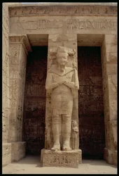 Una de las figuras de pie de Ramsés III como el dios Osiris, lado este del primer patio o, el Salón de las Apariciones, del Templo Mortuorio de Ramsés III, Nuevo Reino