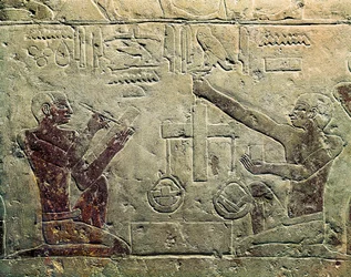 Bajorrelieve que representa a un comerciante y un cliente: una de las figuras usa una balanza mientras la otra toma notas, c.2465-2323 a.C.