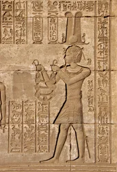 Antigüedad egipcia: mammisi romano conmemorando el nacimiento de Ihy, hijo de Isis - Detalle de relieves e inscripciones jeroglíficas: Emperador Trajano llevando ofrendas a la diosa Hathor - Templo de Hathor, Denderah, Egipto
