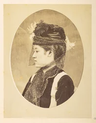 mujer japonesa en vestido europeo, imagen ovalada; retrato de perfil izquierdo de cabeza y hombros de una joven japonesa vestida de europeo, con sombrero y velo,     Fotógrafo: Desconocido  Colección Lucas: Registro fotográfico de la gira mundial de Charle