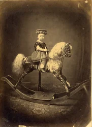 Niña sentada en un caballo balancín moteado