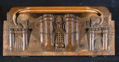 Una misericordia que representa el caballo de Sir Yvain atrapado mientras se baja la reja de entrada de un castillo elaborado, Capilla del New College, Oxford, finales del siglo XIV (madera)