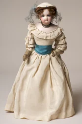 Muñeca de moda de bisque con cabeza giratoria, vestida con un largo vestido crema y sombrero
