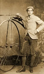 Hombre de pie junto a su biciclo, hacia 1890