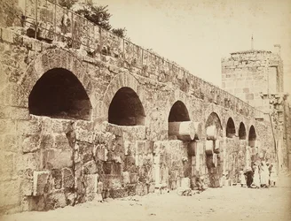 Vista de las murallas de la ciudad de Heliópolis o Baalbek, antigua ciudad siria, ahora Líbano. Un grupo de personas reunidas cerca de la muralla