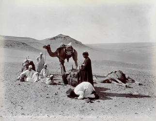 Camelleros egipcios durante una pausa en el desierto. En primer plano, dos miembros del pequeño grupo parecen estar rezando